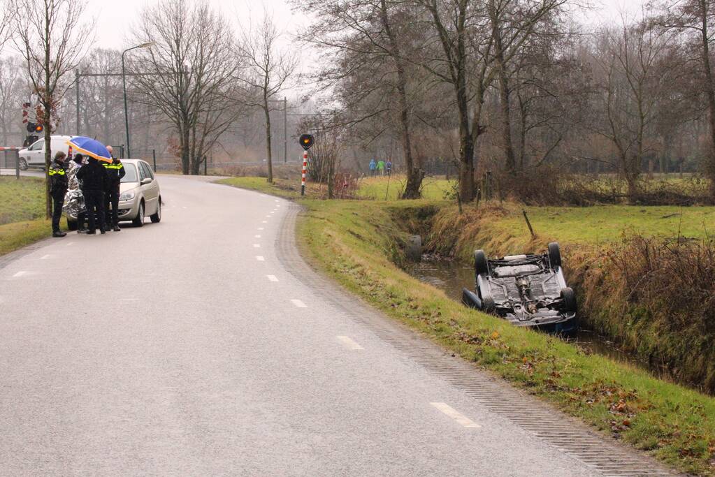 Auto vliegt uit bocht en komt ondersteboven in sloot