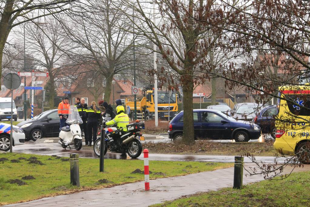 Auto en scooter botsen op rotonde