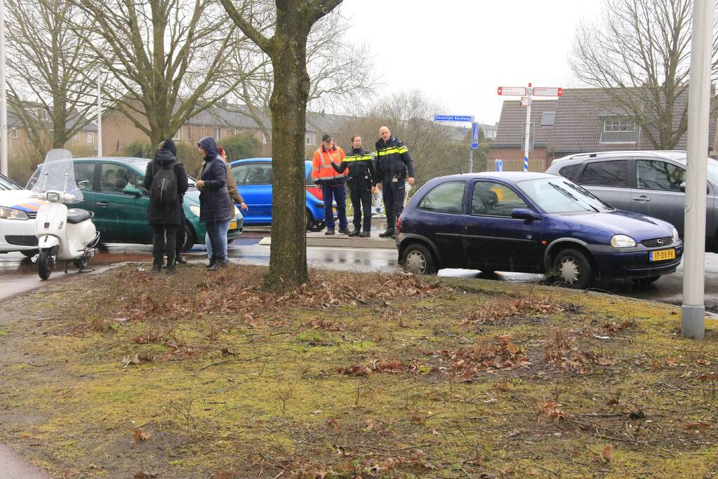 Auto en scooter botsen op rotonde
