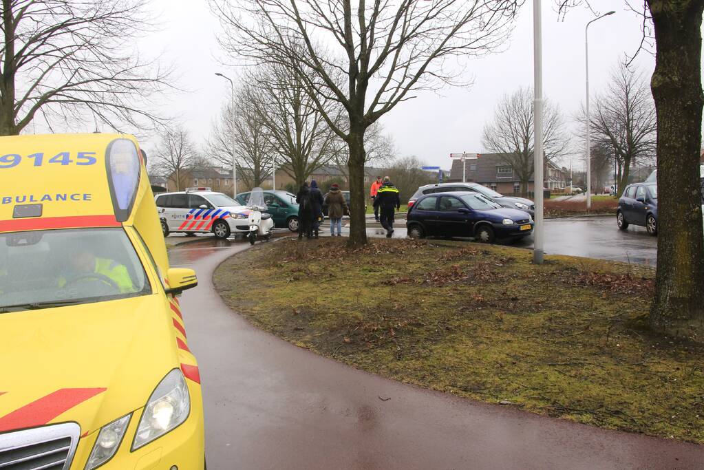 Auto en scooter botsen op rotonde