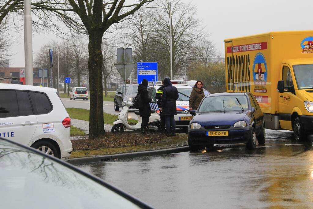 Auto en scooter botsen op rotonde