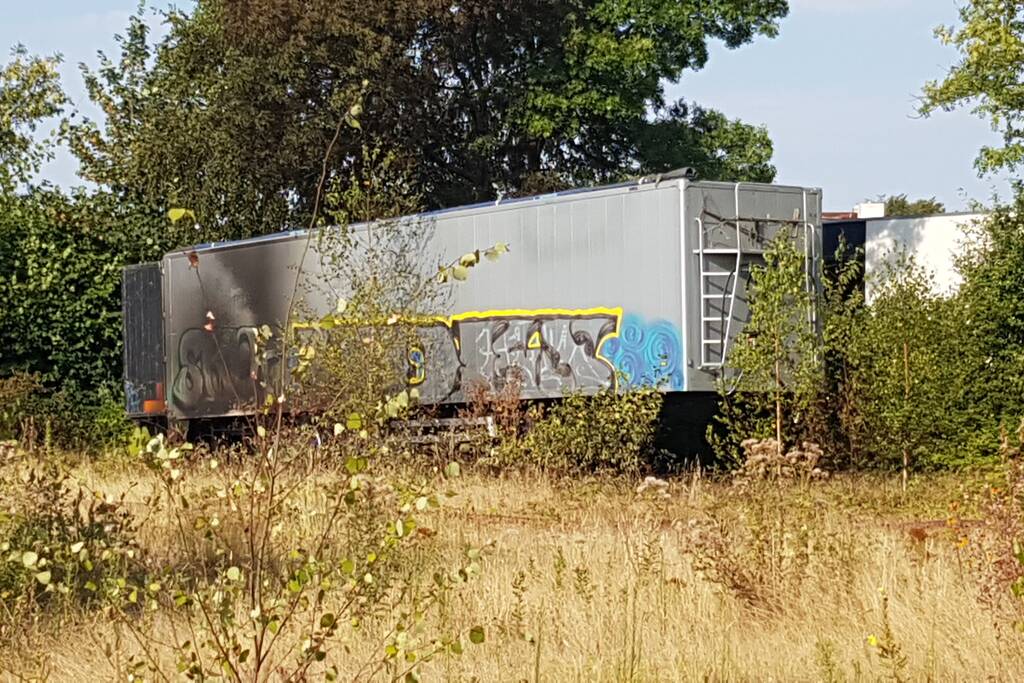 Brand nabij oude trailer in weiland