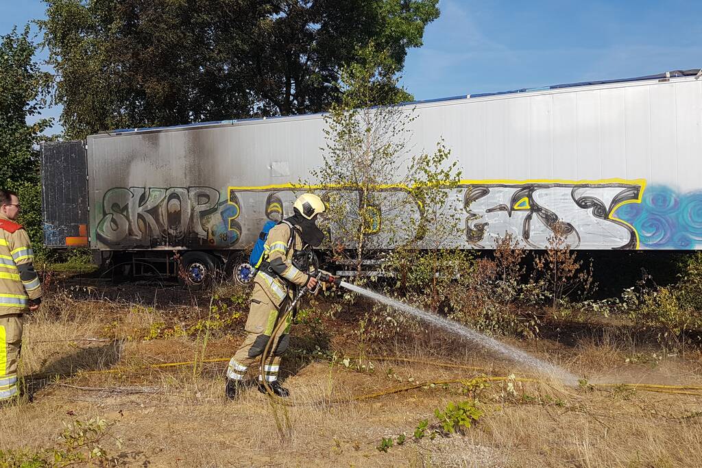 Brand nabij oude trailer in weiland