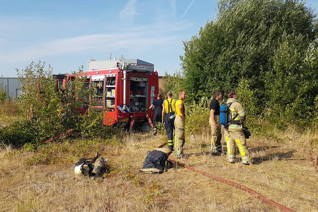Brand nabij oude trailer in weiland