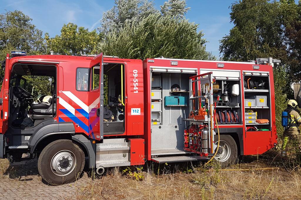 Brand nabij oude trailer in weiland