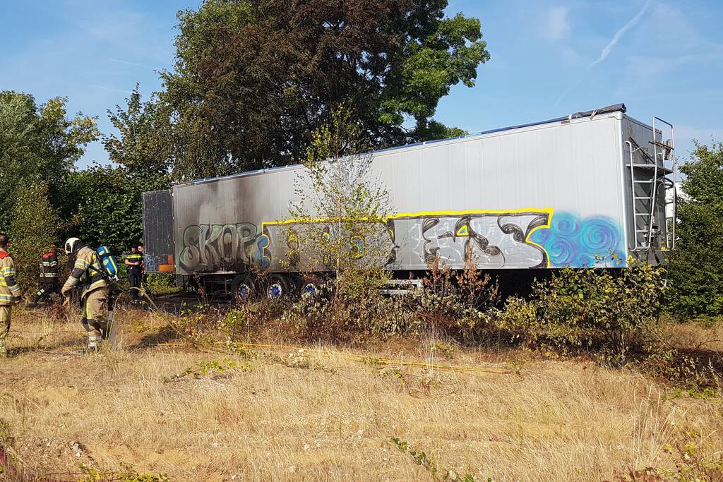 Brand nabij oude trailer in weiland