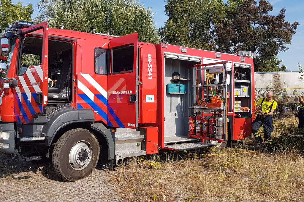 Brand nabij oude trailer in weiland