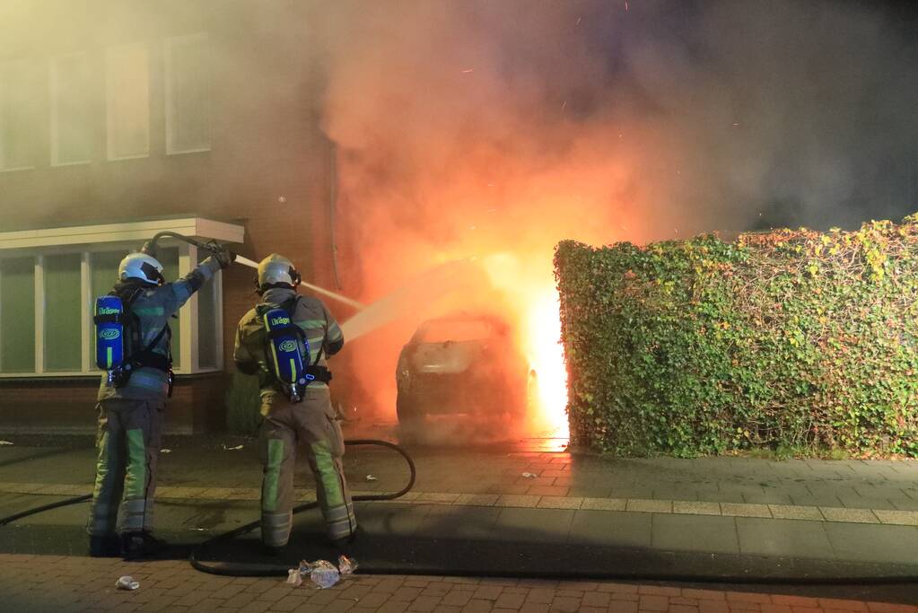 Auto in lichterlaaie onder carport van woning
