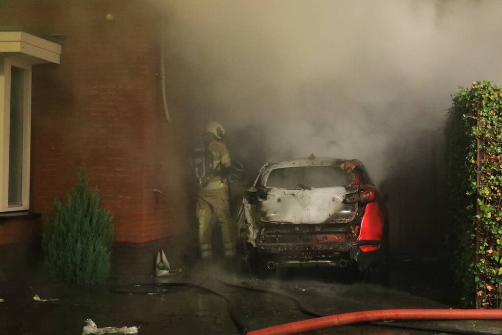 Auto in lichterlaaie onder carport van woning