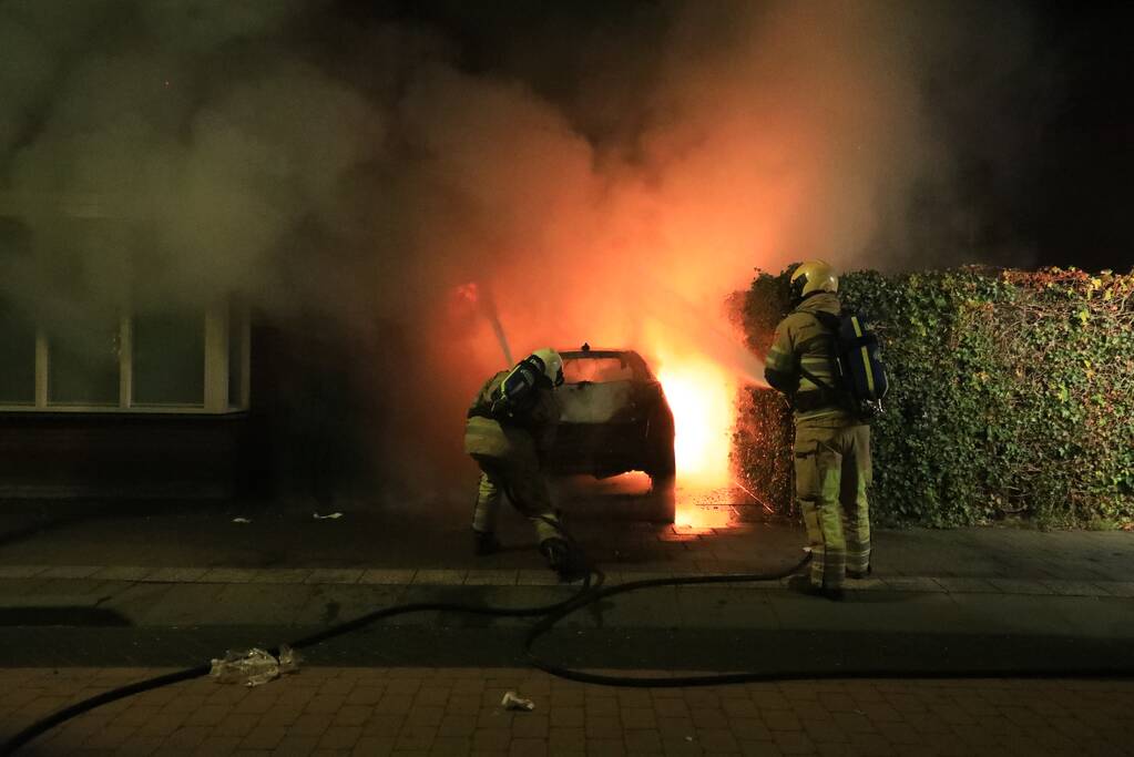 Auto in lichterlaaie onder carport van woning