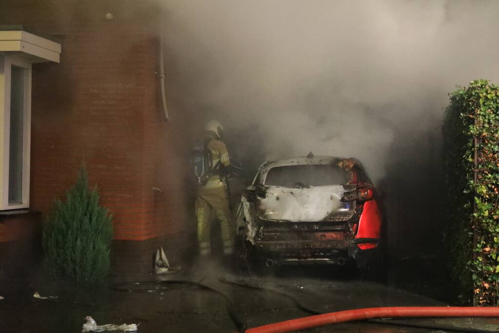 Auto in lichterlaaie onder carport van woning