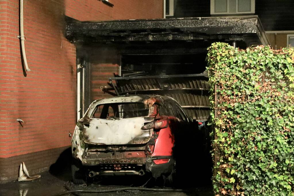 Auto in lichterlaaie onder carport van woning
