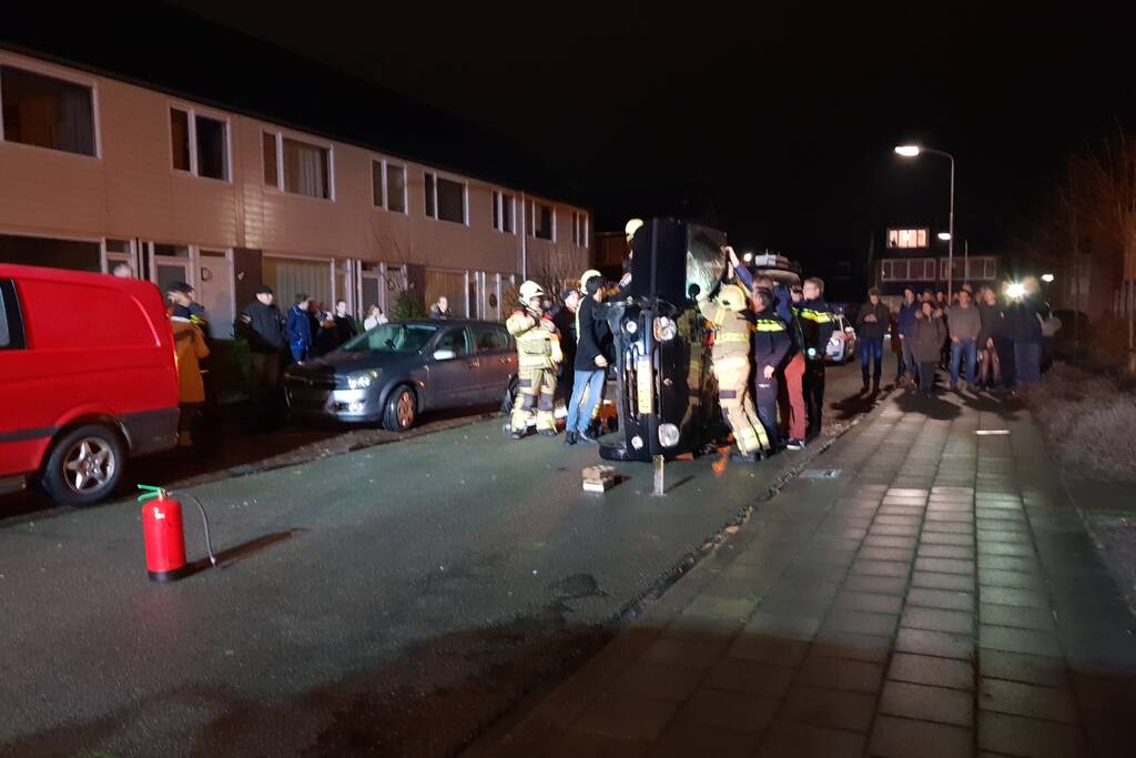 Bestuurster bekneld na auto op zijn kant