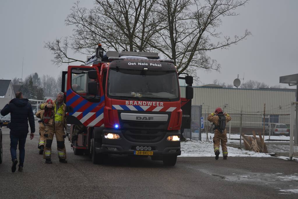 Houtopslag tegen loods aan vat vlam