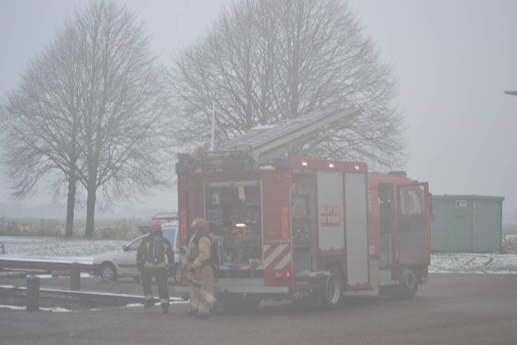 Houtopslag tegen loods aan vat vlam