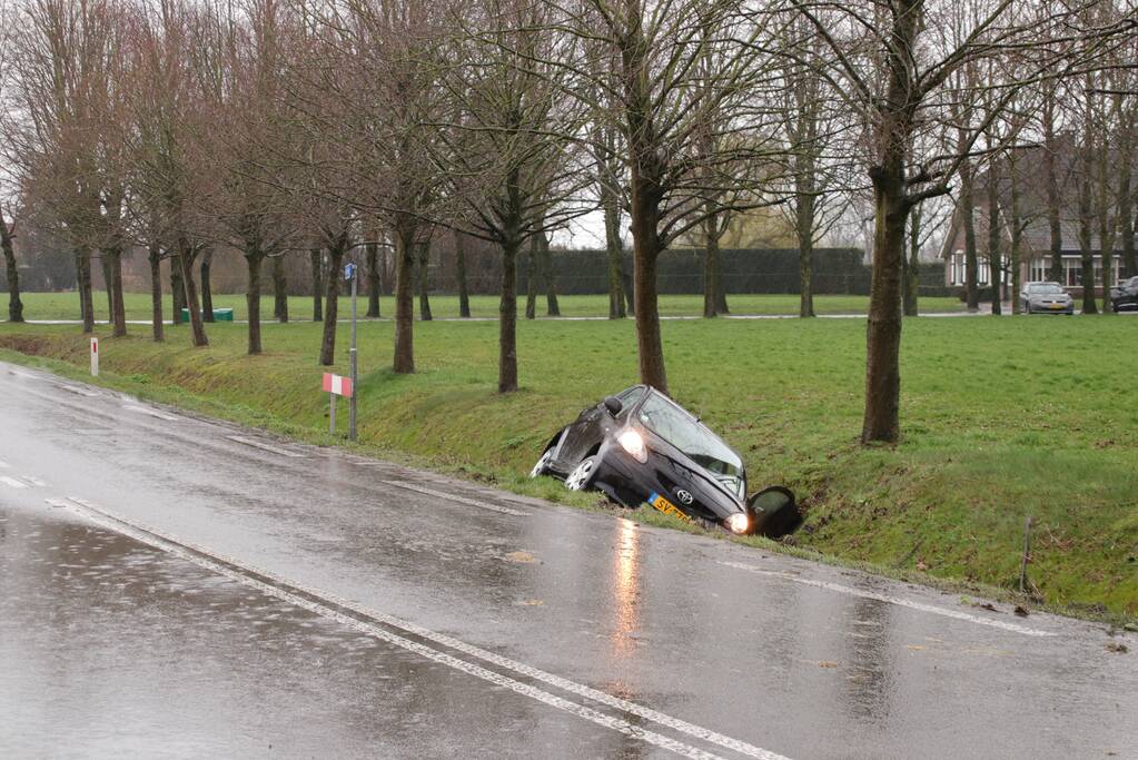 Auto schiet over kruising de sloot in