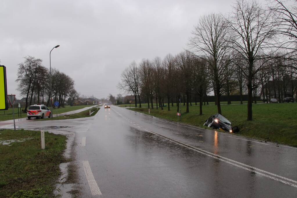 Auto schiet over kruising de sloot in