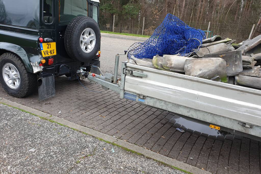 Auto met zware aanhanger dakpannen belandt in vangrail