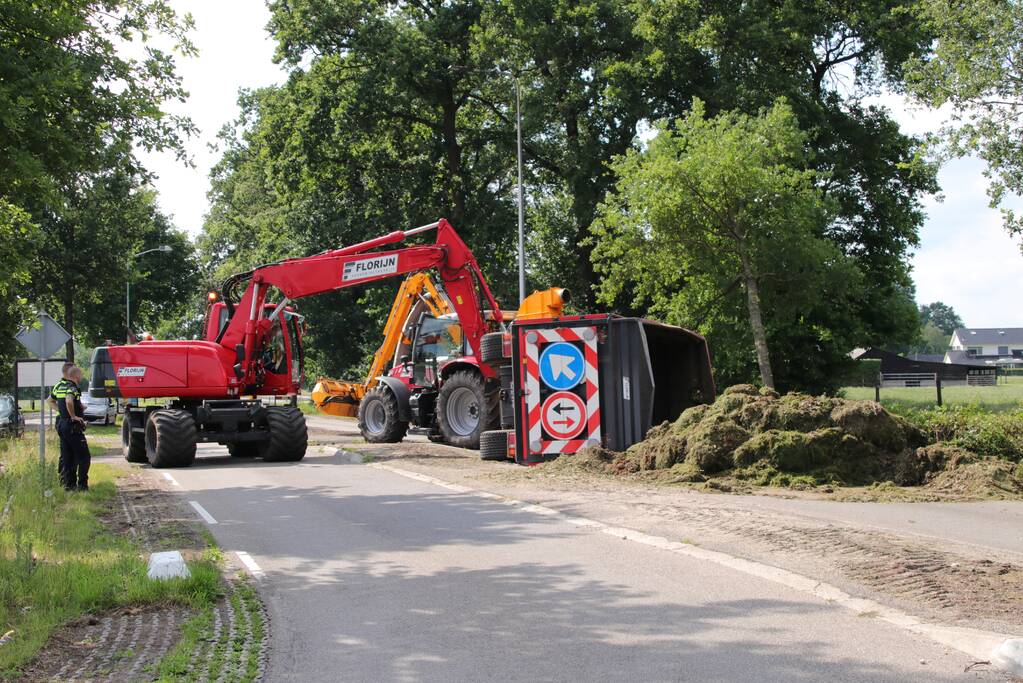 Kar met maai-afval achter trekker kantelt