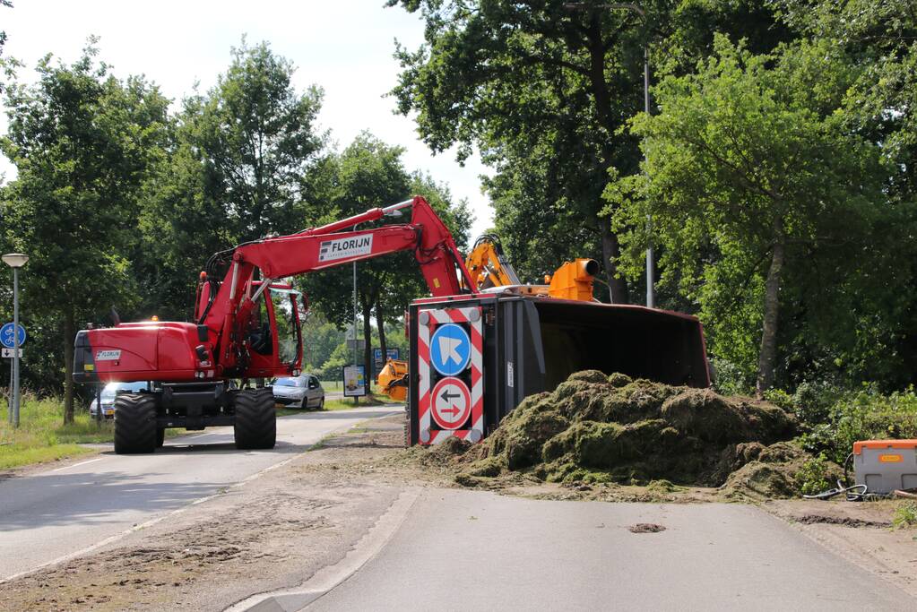 Kar met maai-afval achter trekker kantelt