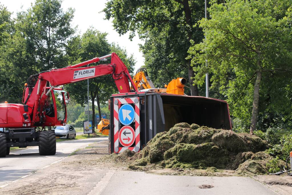 Kar met maai-afval achter trekker kantelt