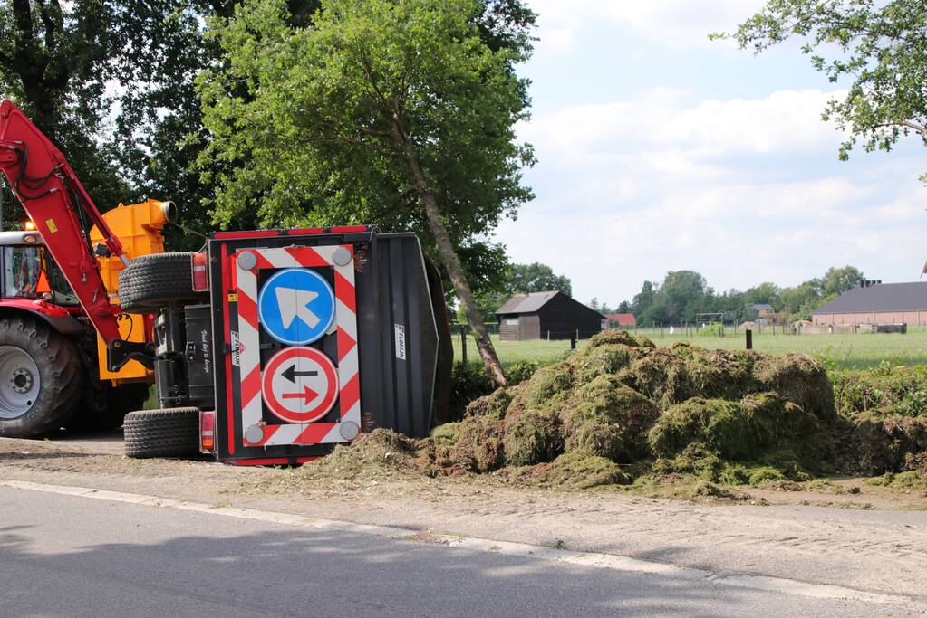 Kar met maai-afval achter trekker kantelt