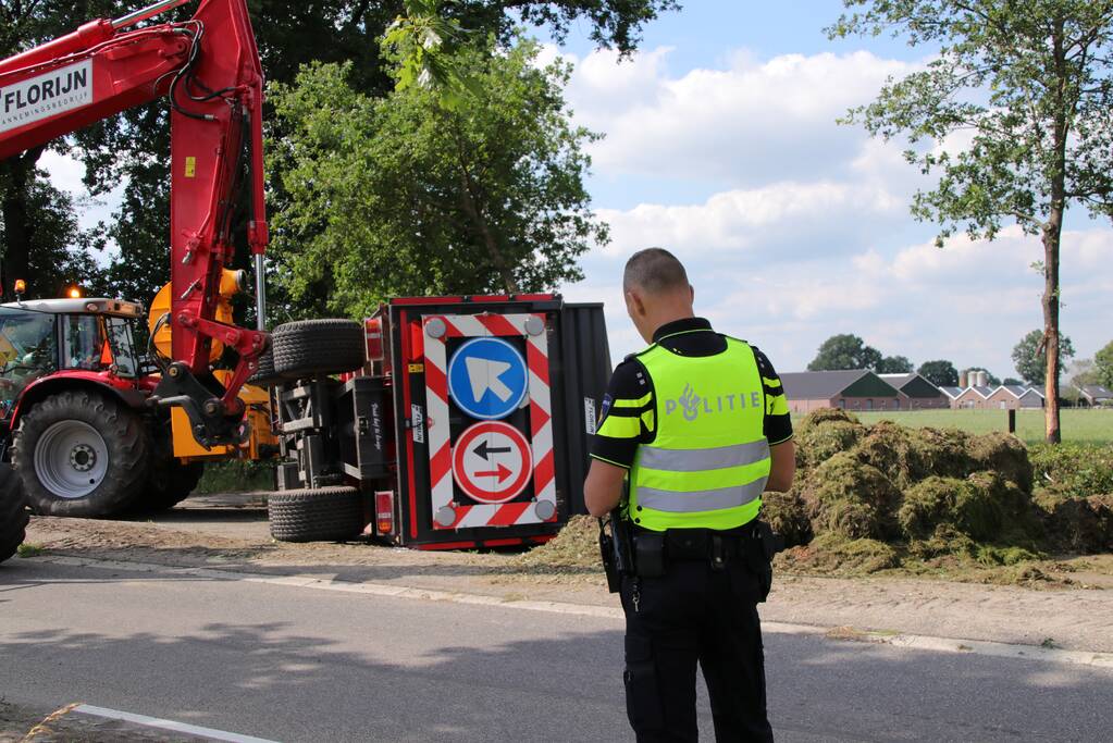 Kar met maai-afval achter trekker kantelt
