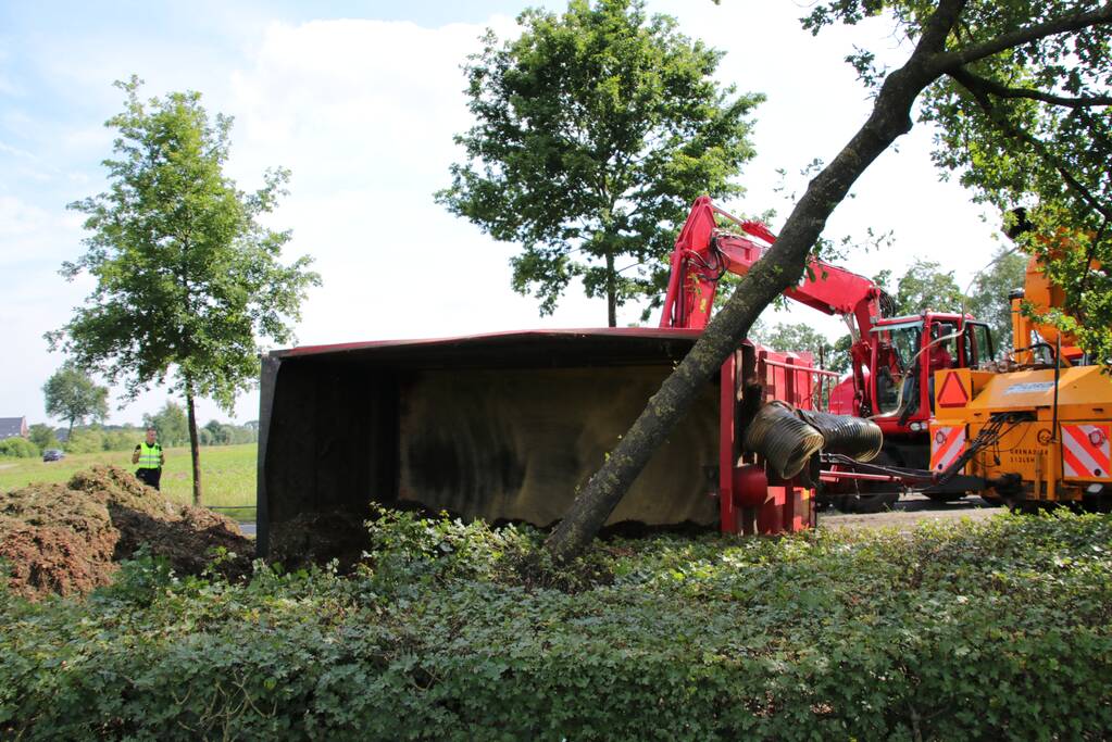 Kar met maai-afval achter trekker kantelt