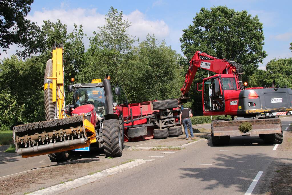 Kar met maai-afval achter trekker kantelt