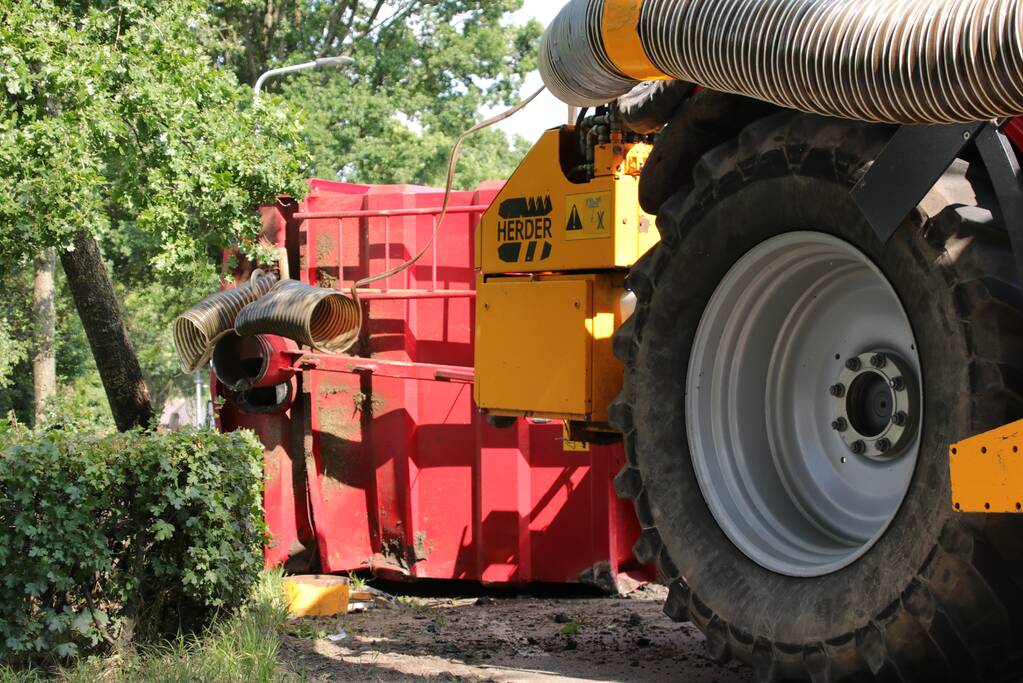 Kar met maai-afval achter trekker kantelt