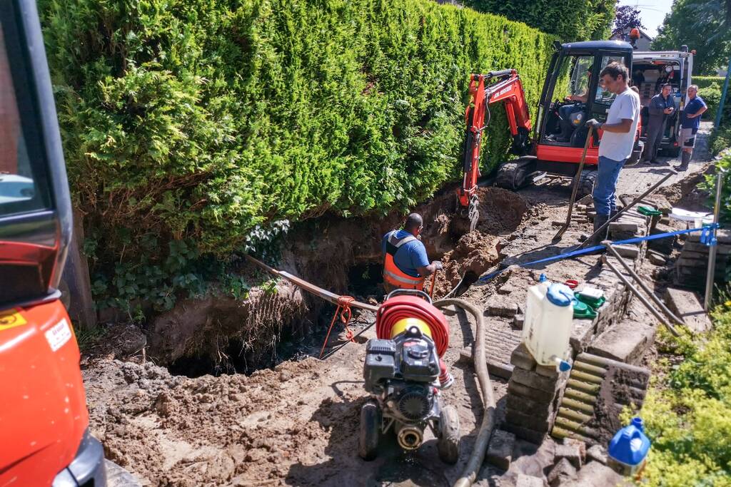 Smalle weg afgesloten door gesprongen waterleiding