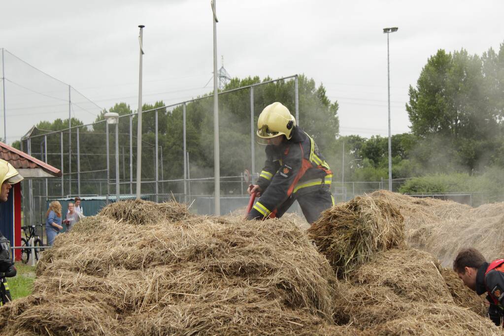Brandweer blust smeulende hooibalen
