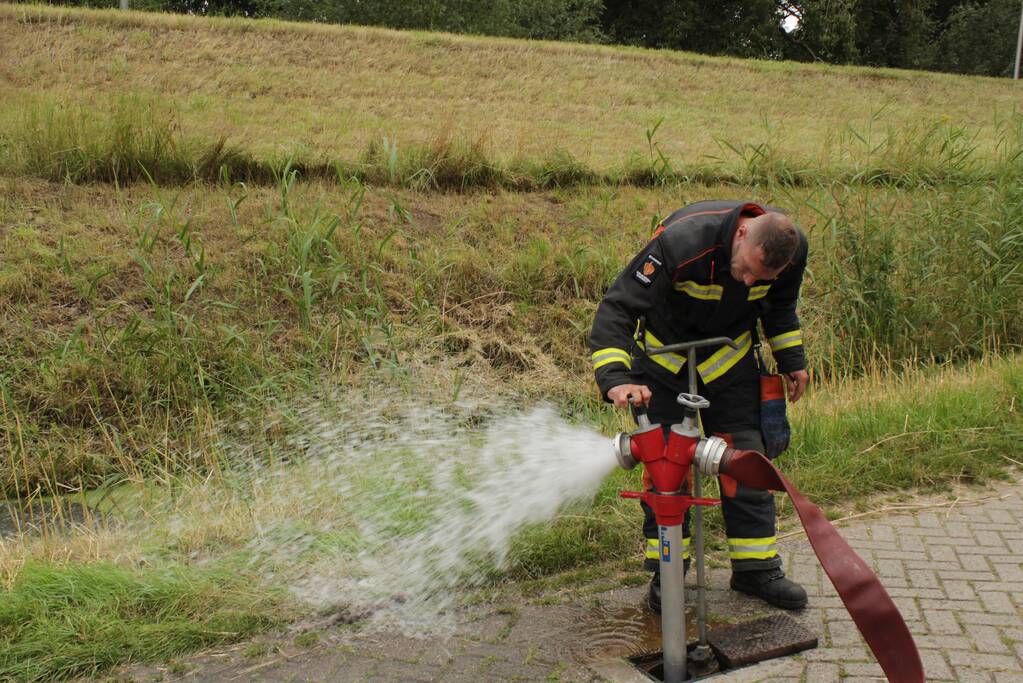 Brandweer blust smeulende hooibalen