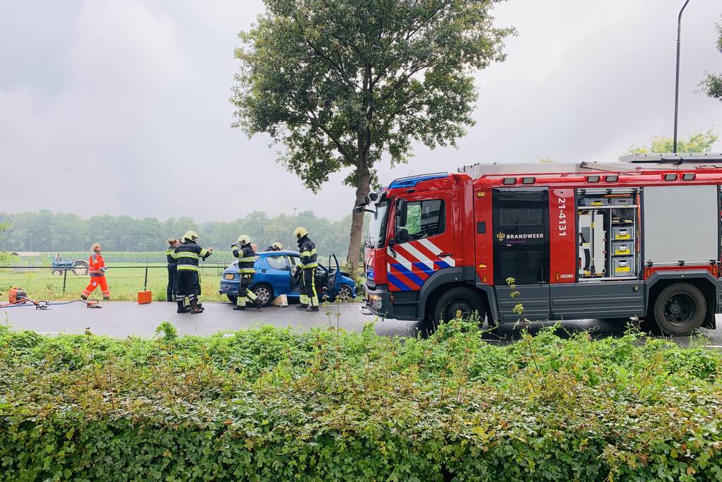 Auto botst tegen boom, bestuurder bekneld