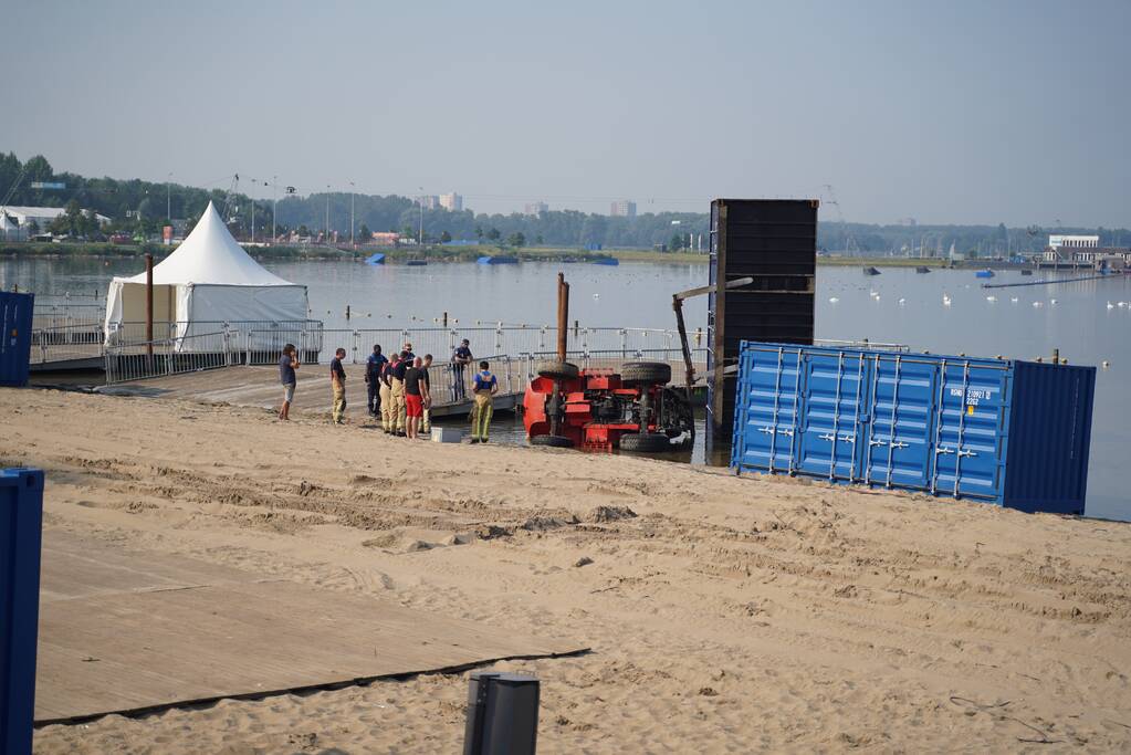 Heftruck met container valt om in water