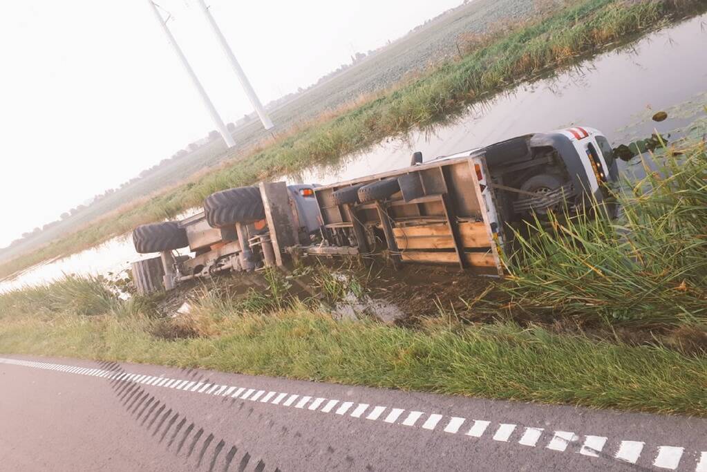 Graafmachine met aanhanger belandt te water