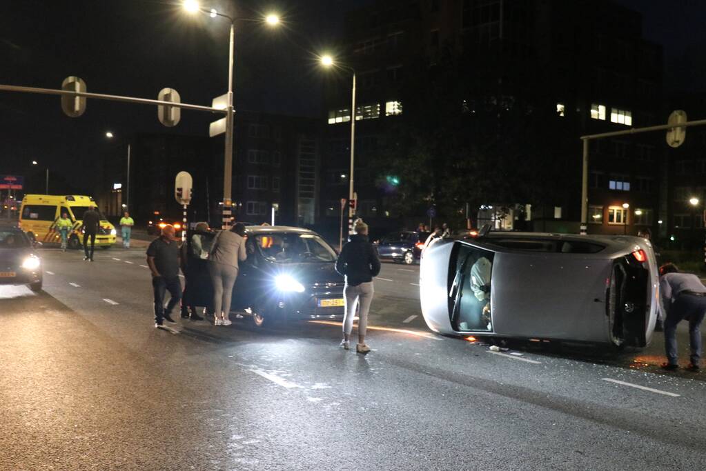 Auto belandt op zijkant na botsing; inzittende gewond bij reddingsactie