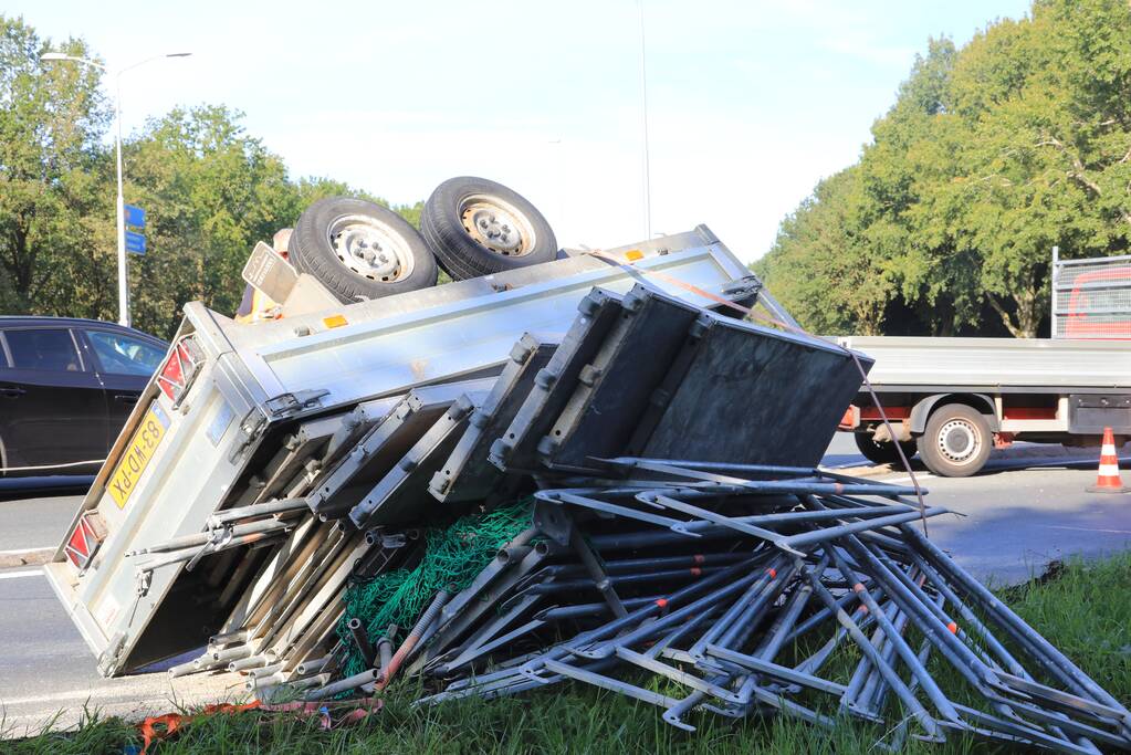 Aanhangwagen met steigerdelen kantelt