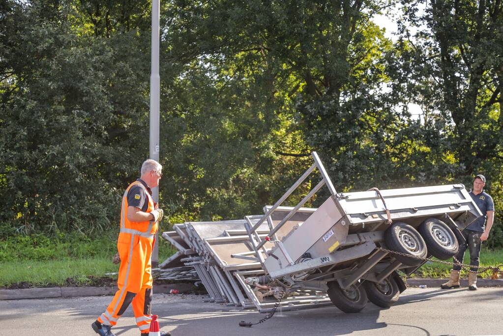 Aanhangwagen met steigerdelen kantelt