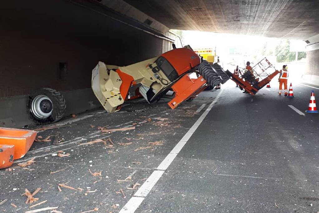 Vrachtwagen met hoogwerker klemgereden onder spoorviaduct