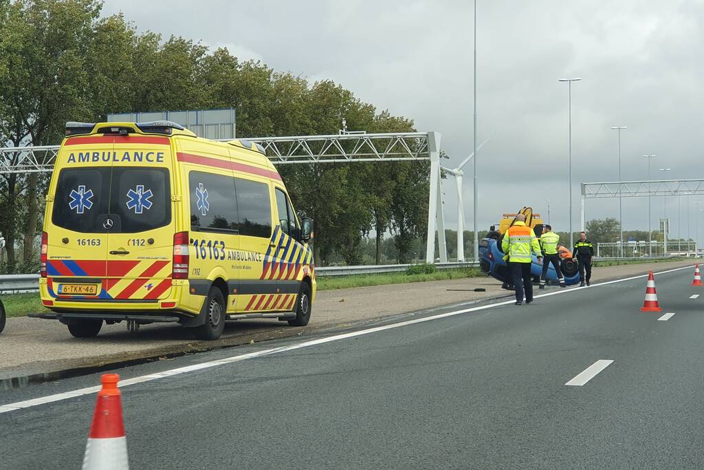 Auto over de kop naast snelweg