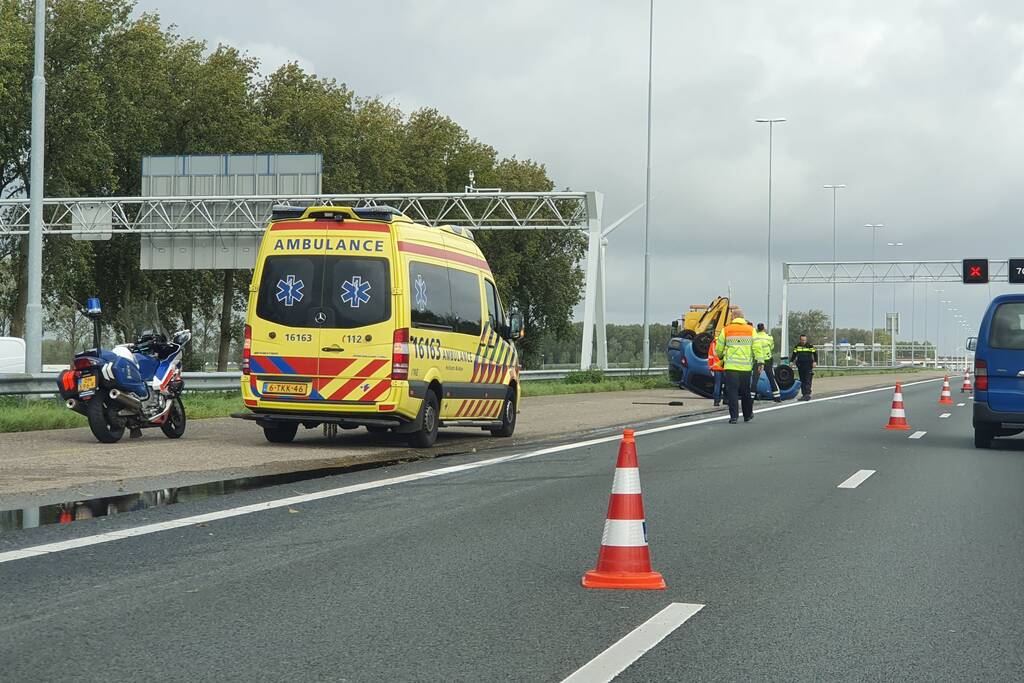 Auto over de kop naast snelweg