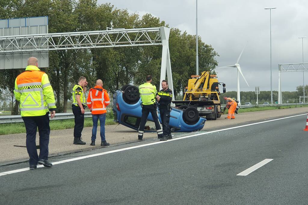 Auto over de kop naast snelweg