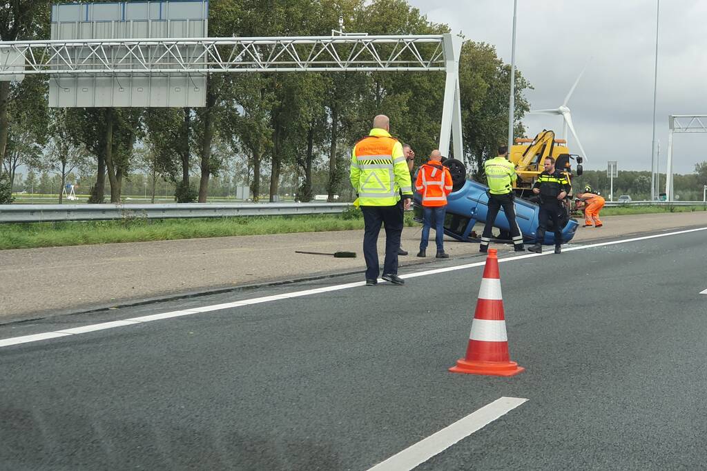 Auto over de kop naast snelweg