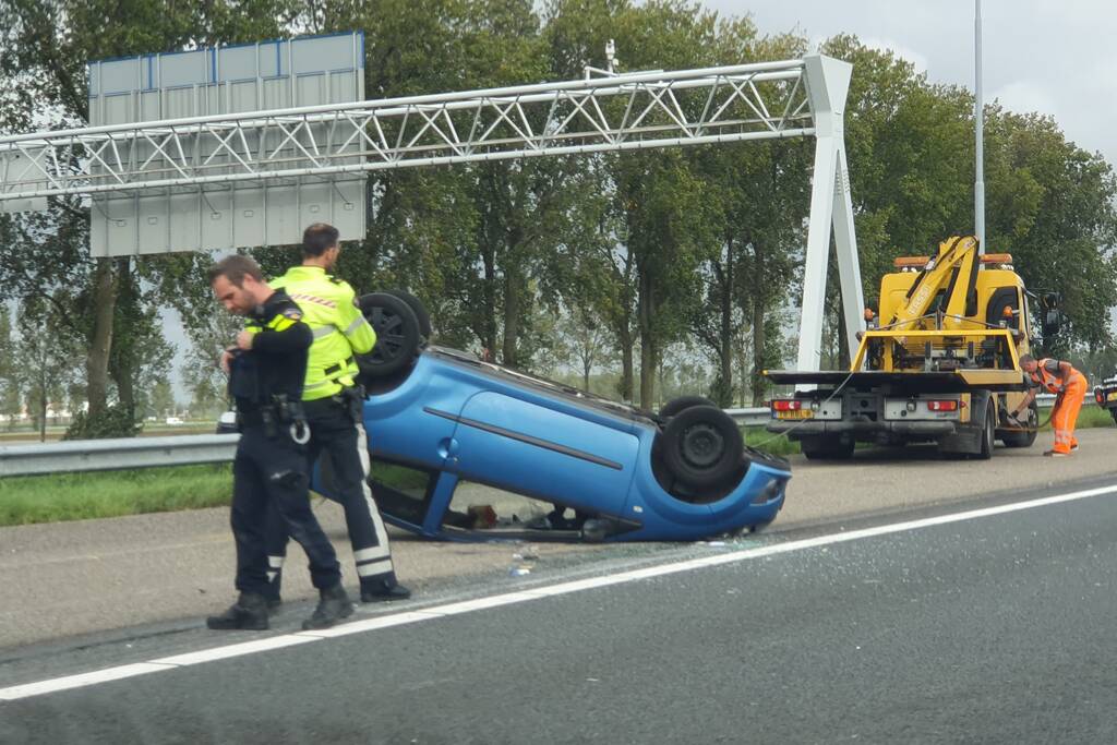 Auto over de kop naast snelweg