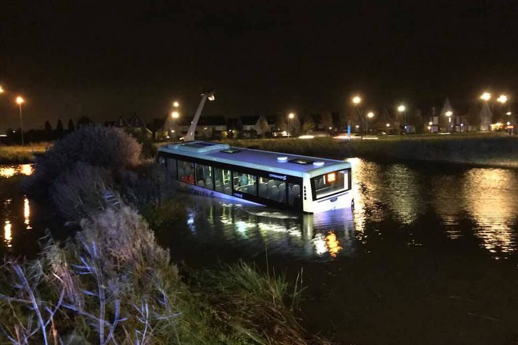 Lijnbus mist bocht en rijdt water in