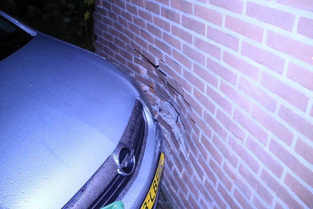 Geparkeerde auto ramt gevel na aanrijding