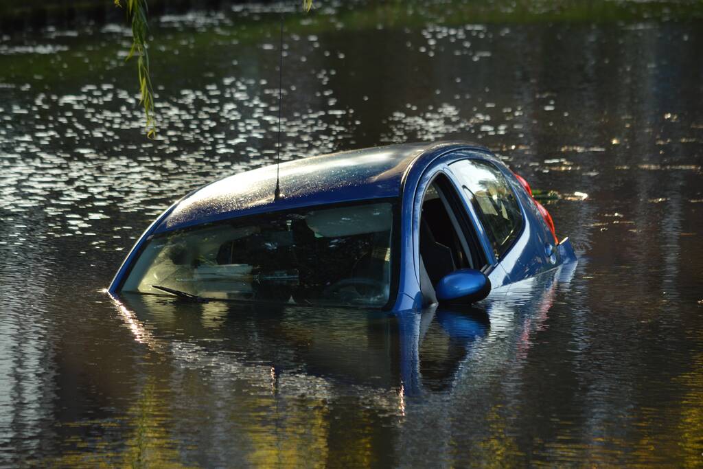 Automobilste rijdt met auto water in