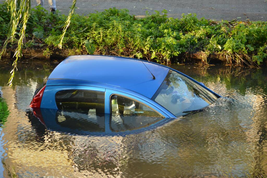 Automobilste rijdt met auto water in