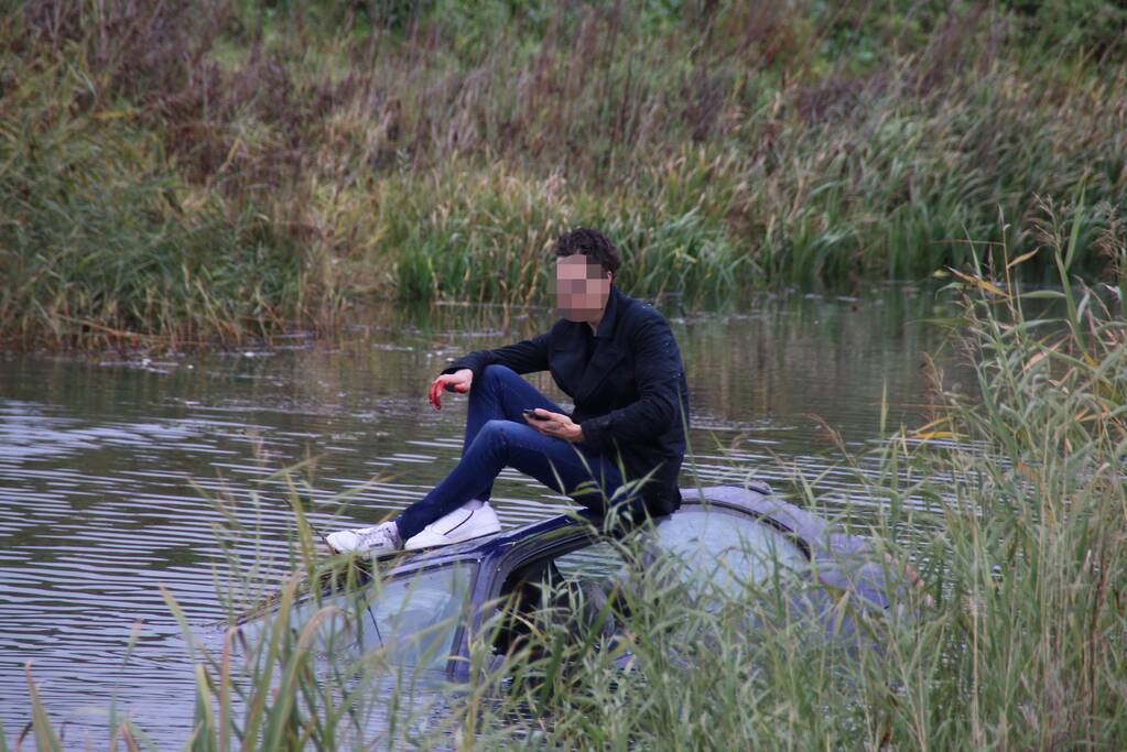 Bestuurder klimt op dak van te water geraakte auto